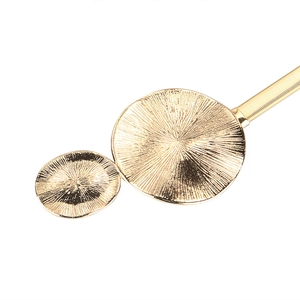 Macro detail of golden metal spring belt with radiant sunburst texture on double circles