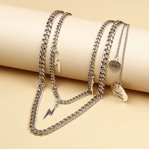 Macro detail of silver layered pants chain featuring lightning bolt charms and engraved Love tag