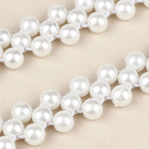 Détail de la chaîne de taille en perles blanches avec décor floral marguerite