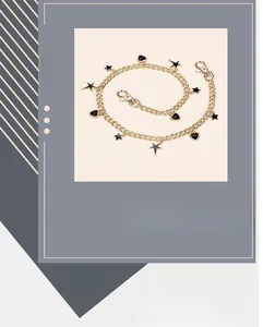 Detail of gold-colored pants chain featuring black enamel star and heart shaped charms