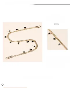 Detailed close-up of gold trousers chain with black star and heart pendants and lobster clasps
