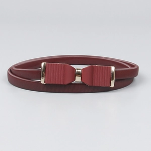 Détail de la ceinture élastique rouge vin avec une boucle dorée en forme de nœud