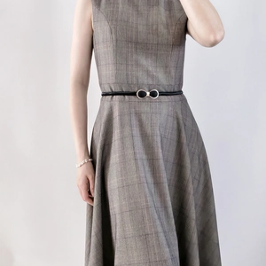 Détail d'une fine ceinture noire avec boucle papillon dorée sur une robe à carreaux