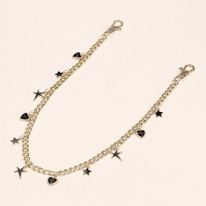 Close-up of gold trousers chain with black enamel star and heart love pendants