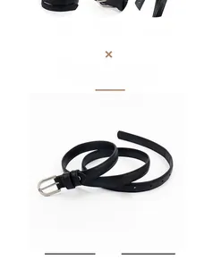 Détail d'une fine ceinture en cuir noir avec boucle à aiguille argentée et trous réglables