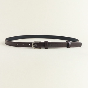 Détail de la ceinture fine en cuir marron foncé avec boucle en D argentée mate