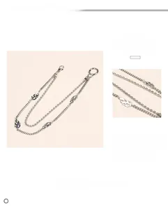 Macro detail of multi-layer alloy trouser chain featuring flame pendant and lobster clasp