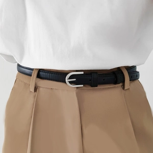 Fine ceinture en cuir noir avec boucle fer à cheval argentée sur pantalon kaki
