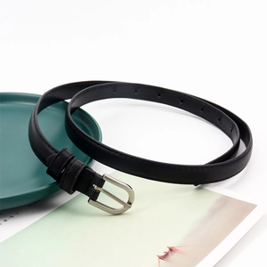 Vue détaillée d'une ceinture fine en cuir noir avec boucle argentée mate sur une assiette