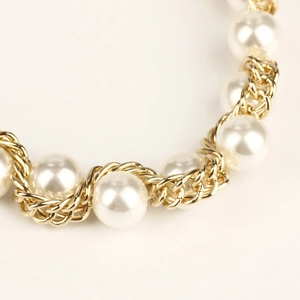 Makroaufnahme einer goldenen Kordelkette mit eleganten weißen Perlen für Körperschmuck