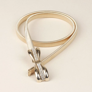 Détail de la ceinture dorée élastique avec boucle en forme de nœud ornée de strass
