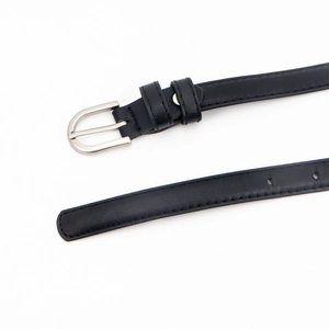 Détail d'une fine ceinture en cuir noir avec boucle argentée en D et coutures