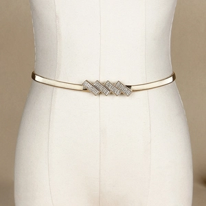 Elastic gold metal waist chain belt with sparkling rhinestone buckle on a white mannequin