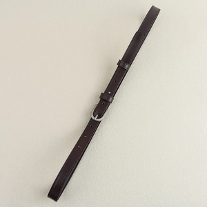 Gros plan d'une fine ceinture en cuir marron foncé avec boucle fer à cheval en argent