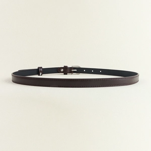 Détail de la fine ceinture en cuir marron foncé avec boucle ardillon argentée