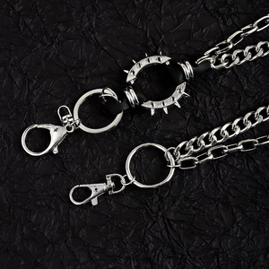 Détail de chaînes de taille punk argentées avec pointes et fermoirs mousquetons
