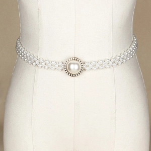 Elegant pearl waist belt with gold rhinestone center buckle on minimalist background