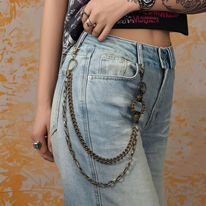 Détail d'une chaîne de pantalon punk en bronze avec anneaux et disque à rivets sur jean