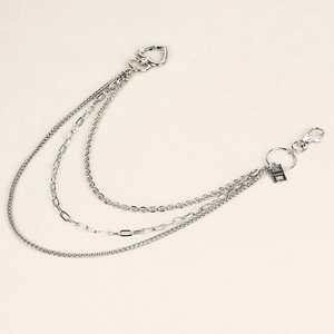 Close-up of triple-layered metal pant chain featuring a heart buckle and engraved gold bar tag