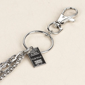 Detail of layered silver metal hip hop pant chain with Credit Suisse gold bar pendant