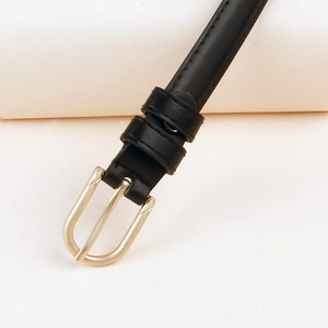 Détail d'une fine ceinture en cuir noir avec boucle dorée en U et coutures précises