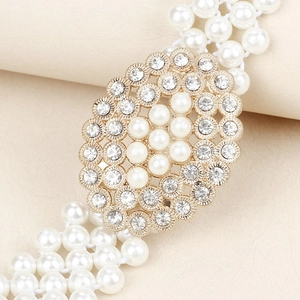 Dettaglio cintura di perle con fibbia ovale di strass su ecopelle beige