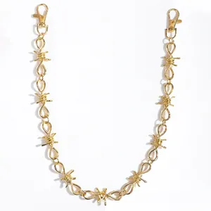 Detail of golden punk style trouser chain with barbed wire links and lobster clasps