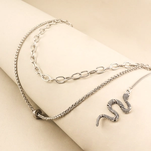 Detailed close-up of double-layered silver chain with textured snake pendant and ring clasp