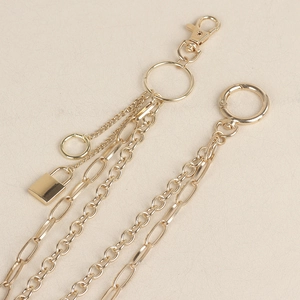 Detail view of layered gold chain with lobster clasp, spring ring, and small lock pendant