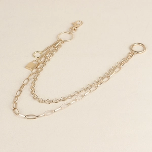 Close-up of double-layered light gold waist chain with metal rings and a small padlock
