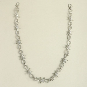 Detailed view of silver barbwire-style metal trouser chain with lobster clasps