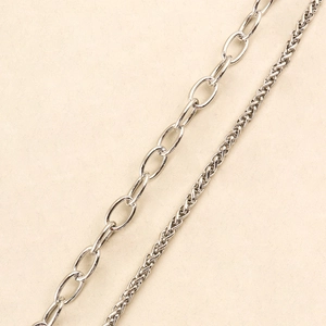 Close-up detail of silver metal chains featuring oval links and tightly woven textures