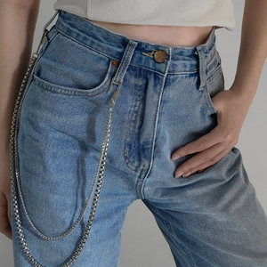 Close-up of double-layer silver metal waist chains on blue washed denim jeans