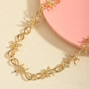 Close-up of golden barbed wire style chain with twisted metal links on a neutral background