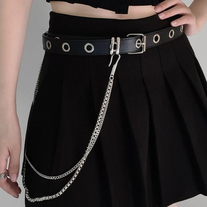 Detail of punk style black leather eyelet belt with double silver metal chains on a skirt