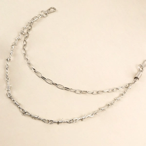 Detailed view of silver double-layered trousers chain with barbed wire and punk links