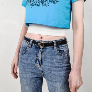 Women's slim black leather belt with golden triangle buckle on light wash denim jeans