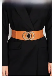 Detail of a brown elastic waist belt featuring a textured golden double ring buckle