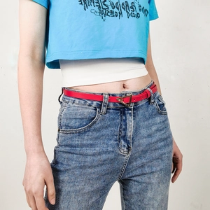 Detail of red leather belt with iconic gold triangle buckle styled on blue denim jeans
