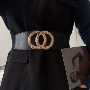 Detail of a wide black elastic waist belt for women with textured gold interlocking rings
