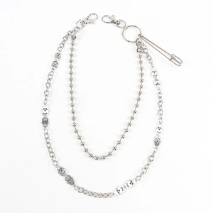Detail of silver double-layered metal trousers chain with skull charms and safety pin