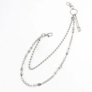 Detail of punk silver double-layer trousers chain with skull charms and safety pin