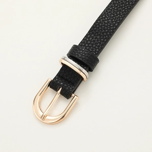 Détail de la ceinture en cuir noir avec boucle fer à cheval dorée et anneau bicolore en métal
