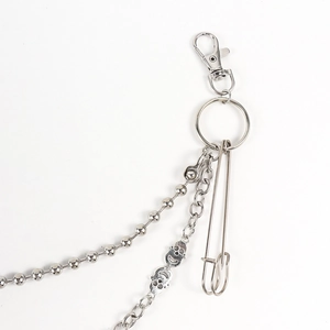 Detail of hip hop pants chain with punk skull pendant, lobster clasp and large safety pin