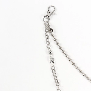 Detail of double punk pants chain with silver skull charms and metallic lobster clasp