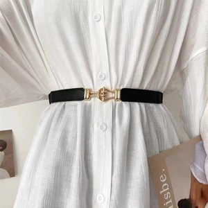 Detail of a thin black leather belt with a geometric gold metal buckle on a white shirt