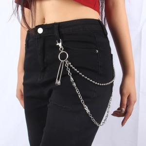 Detail of silver metal double-layer trousers chain with skull charms and safety pin