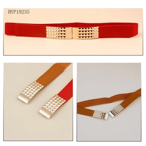 Detail view of elastic waist belts in red and camel with gold pyramid stud metal buckles