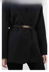 Detail of thin black belt with golden leaf-shaped metal buckle on black dress blazer