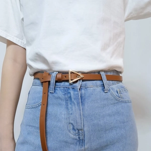 Detail view of a brown leather belt with a golden triangular buckle on denim jeans
